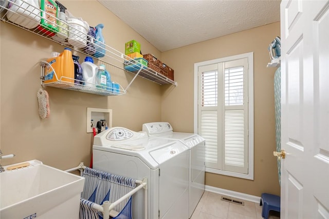 laundry room featuring visible vents, a sink, a textured ceiling, separate washer and dryer, and laundry area