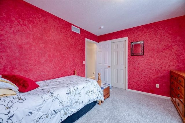 bedroom with carpet floors, visible vents, a textured ceiling, baseboards, and wallpapered walls