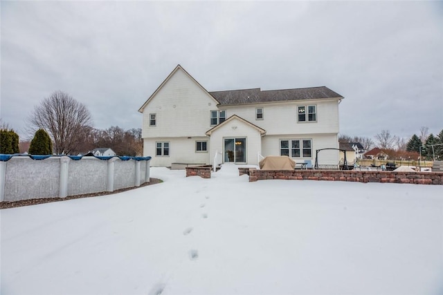 snow covered rear of property featuring a covered pool