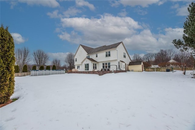 snow covered house featuring fence