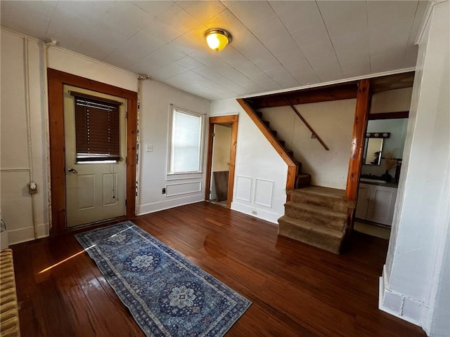 foyer with wood-type flooring, a decorative wall, and stairs