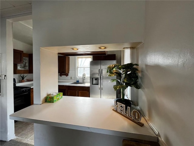 kitchen featuring stainless steel fridge, electric range, light countertops, a sink, and light tile patterned flooring