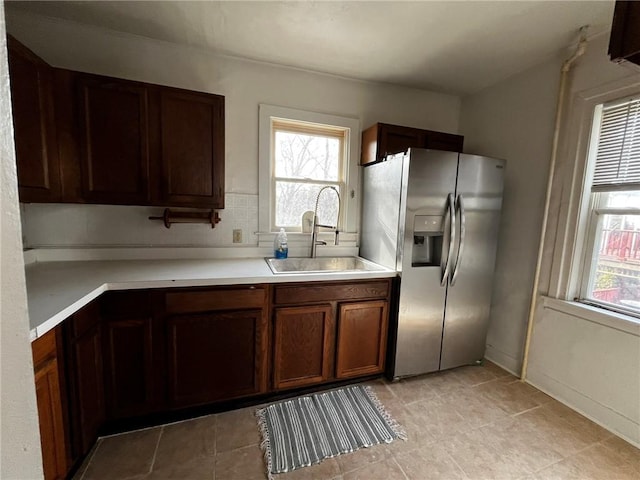 kitchen featuring a wealth of natural light, stainless steel fridge, light countertops, and a sink