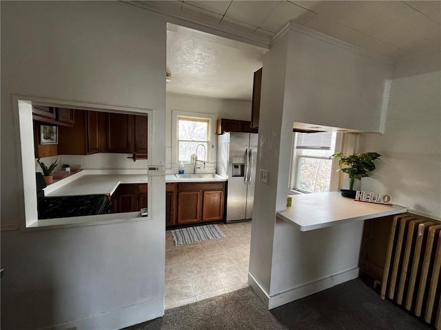 kitchen with light countertops, radiator, stainless steel fridge, and a sink