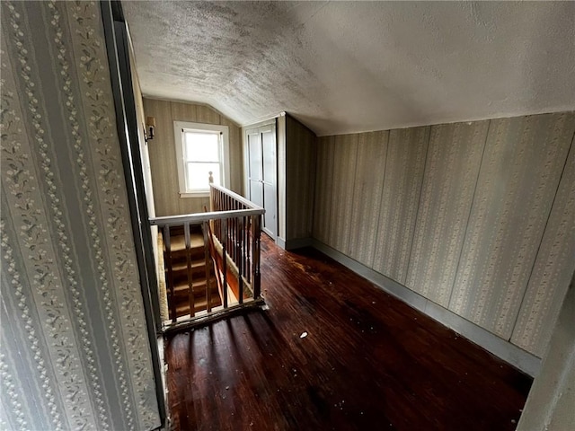 additional living space featuring lofted ceiling, dark wood-style floors, baseboards, and a textured ceiling