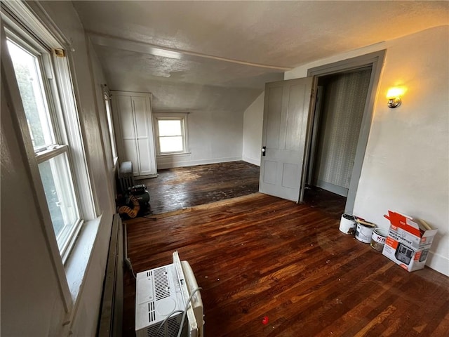 living area with heating unit, wood-type flooring, and vaulted ceiling