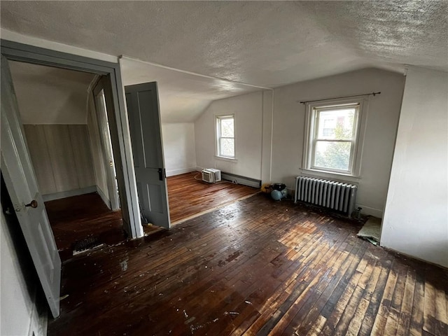 bonus room with a textured ceiling, radiator heating unit, baseboard heating, and hardwood / wood-style flooring