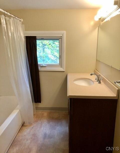 bathroom featuring shower / bath combo, vanity, and baseboards