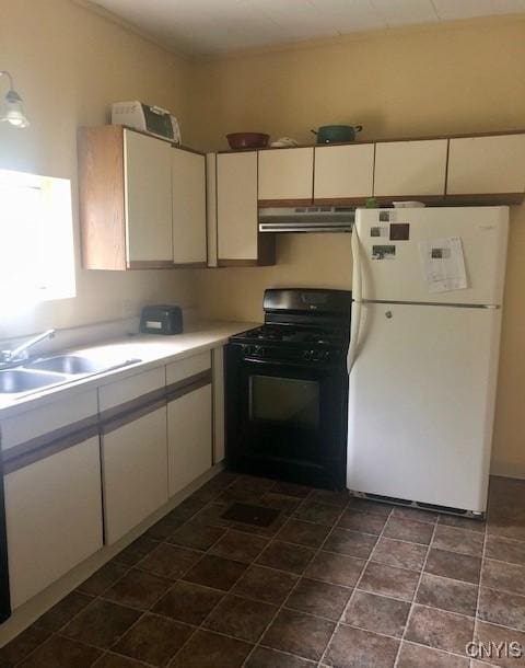 kitchen with under cabinet range hood, a sink, black gas stove, white cabinetry, and freestanding refrigerator