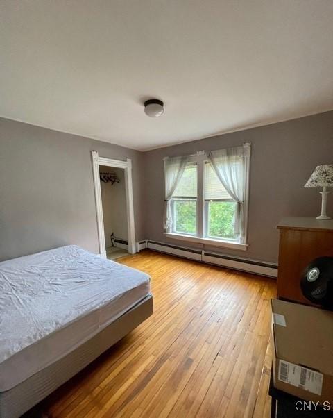 bedroom with light wood-type flooring and baseboard heating