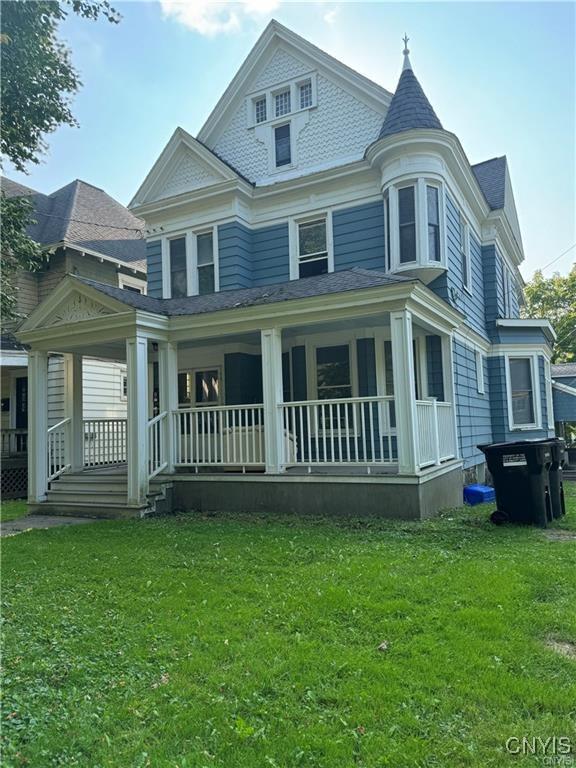 victorian house with a porch and a front lawn