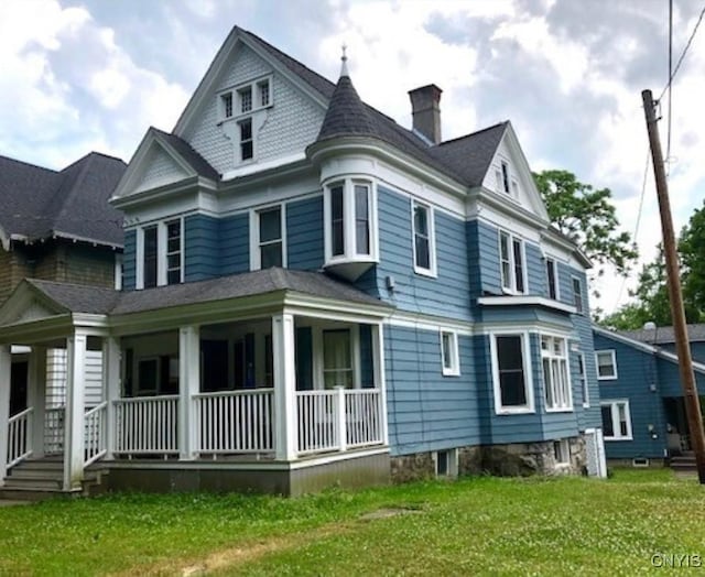 rear view of house with a chimney, a porch, and a yard