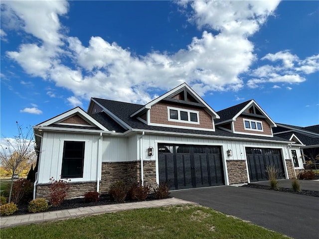 view of front of home featuring board and batten siding, stone siding, and driveway