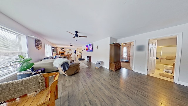 bedroom featuring a ceiling fan, ensuite bathroom, baseboards, and wood finished floors