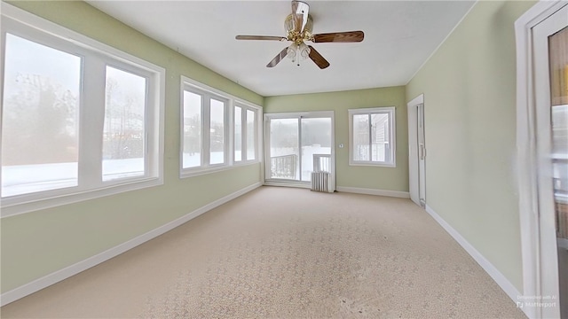 unfurnished sunroom with radiator and ceiling fan