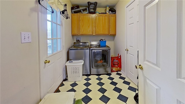 clothes washing area with washer and dryer, cabinet space, and light floors