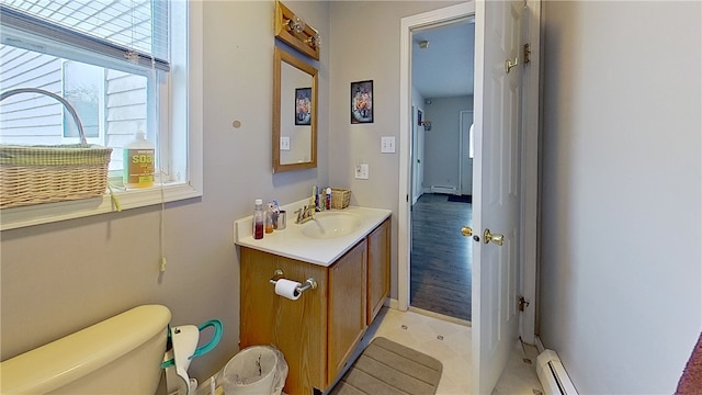 bathroom featuring a baseboard heating unit, vanity, and toilet