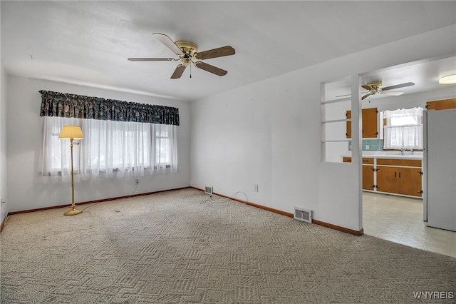 spare room featuring light carpet, plenty of natural light, visible vents, and baseboards