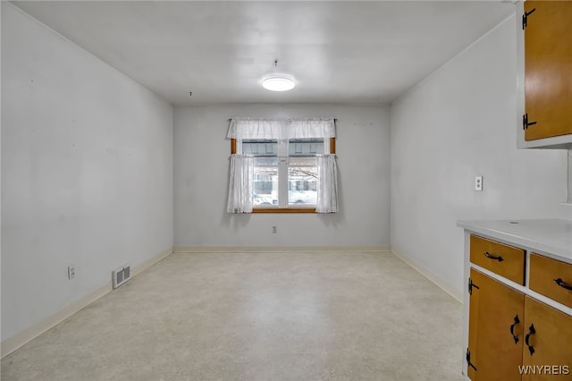 unfurnished dining area with finished concrete flooring, visible vents, and baseboards