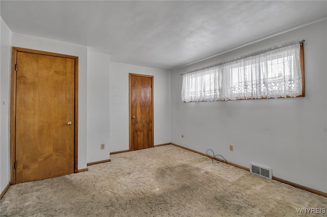 unfurnished bedroom with carpet, a closet, visible vents, and baseboards