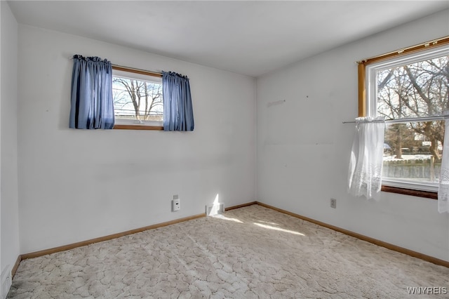 empty room with carpet, visible vents, and baseboards