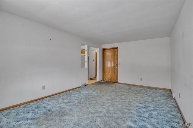 empty room featuring carpet floors, visible vents, and baseboards