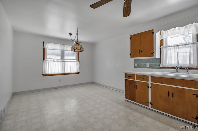 kitchen featuring light floors, brown cabinetry, a sink, and light countertops