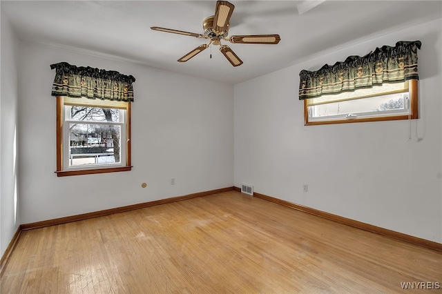 spare room with light wood-type flooring, a healthy amount of sunlight, and visible vents