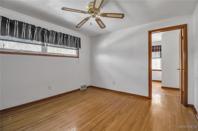 spare room featuring light wood finished floors, visible vents, baseboards, and a ceiling fan