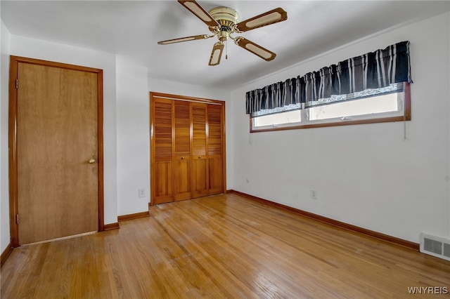 unfurnished bedroom featuring a closet, visible vents, light wood-style flooring, ceiling fan, and baseboards