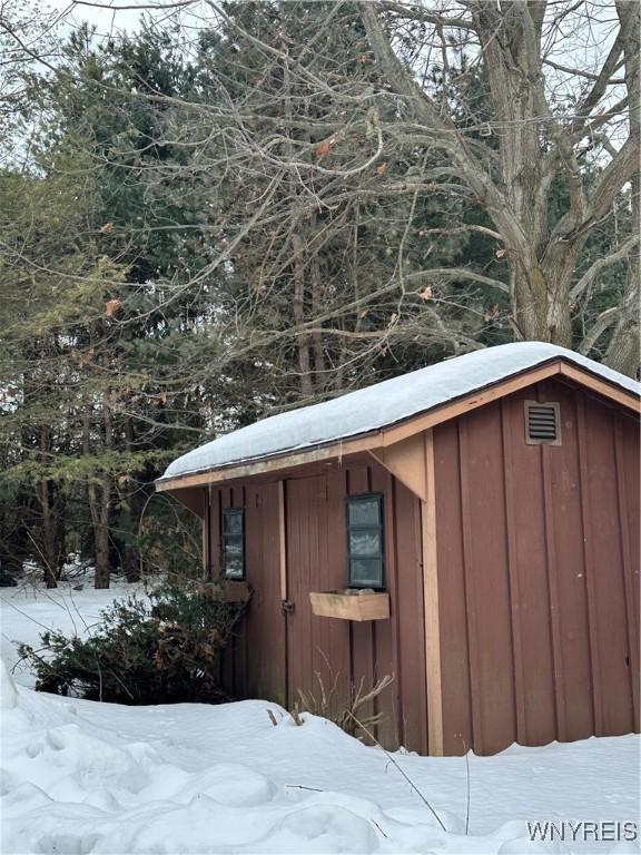 snow covered structure featuring an outbuilding