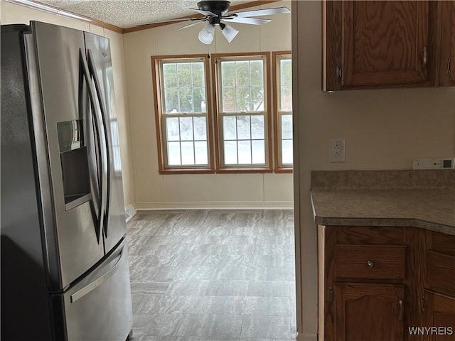 kitchen featuring a textured ceiling, ceiling fan, tile patterned floors, stainless steel fridge, and crown molding