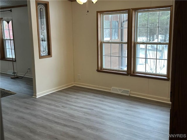 unfurnished dining area featuring wood finished floors, visible vents, and baseboards