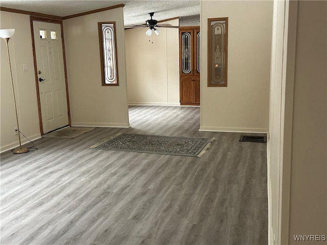 foyer with a textured ceiling, ceiling fan, wood finished floors, visible vents, and crown molding