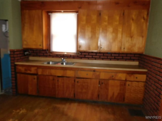 kitchen featuring light countertops, wood finished floors, a sink, and brown cabinets