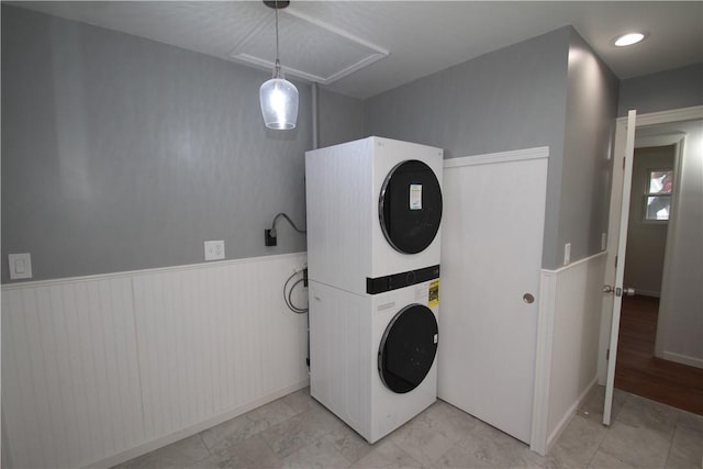 laundry area featuring stacked washer / drying machine, laundry area, and wainscoting