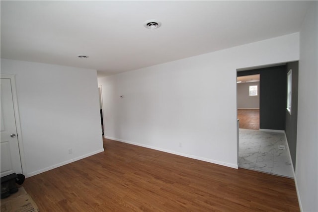 spare room with wood finished floors, visible vents, and baseboards