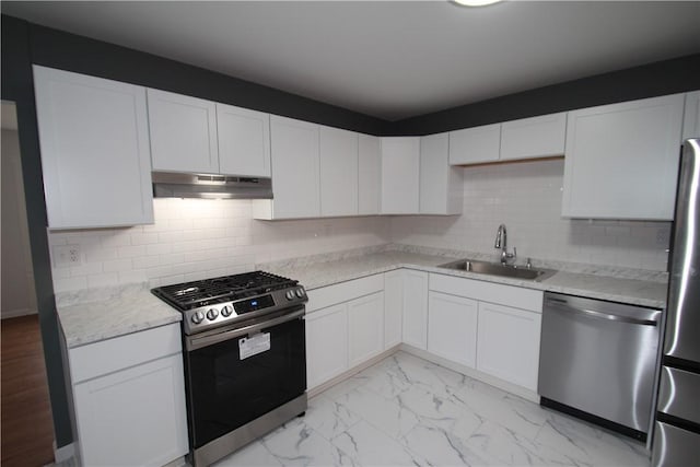 kitchen featuring marble finish floor, appliances with stainless steel finishes, white cabinets, a sink, and under cabinet range hood