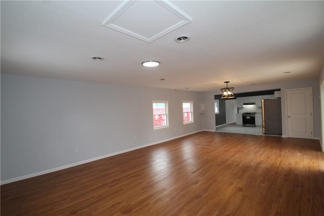 unfurnished living room with visible vents, baseboards, and wood finished floors