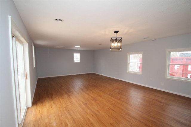 spare room featuring light wood-type flooring, baseboards, and a wealth of natural light