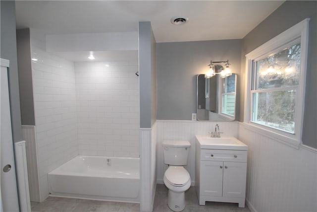 full bath featuring a wainscoted wall, visible vents, toilet, tub / shower combination, and vanity