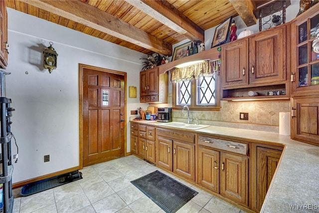 kitchen featuring light countertops, tasteful backsplash, a sink, and beam ceiling