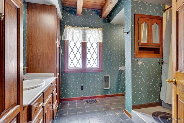 bathroom featuring baseboards, beamed ceiling, and wallpapered walls