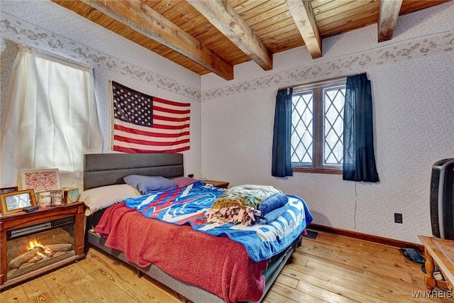 bedroom featuring wood ceiling, baseboards, hardwood / wood-style floors, beamed ceiling, and wallpapered walls