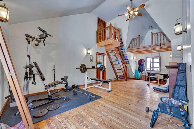 workout room with high vaulted ceiling, wood finished floors, a ceiling fan, and baseboards