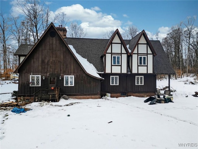 view of front facade with a garage, roof with shingles, and a chimney