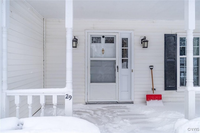 snow covered property entrance featuring a porch