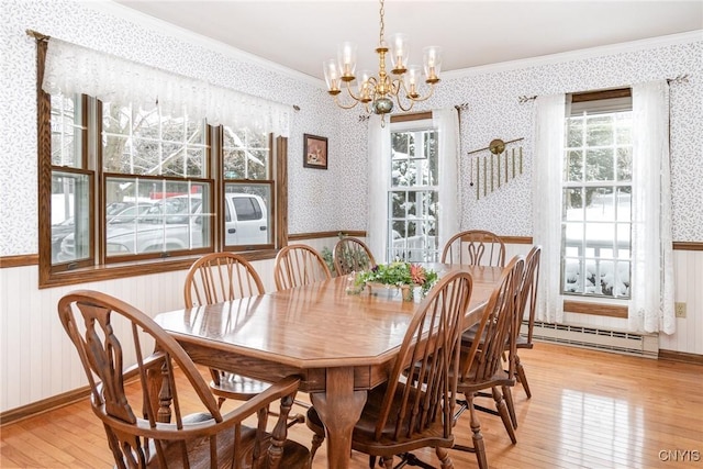 dining room with wallpapered walls, ornamental molding, baseboard heating, and wainscoting