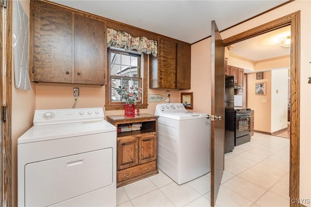 laundry area with crown molding, light tile patterned floors, cabinet space, washer and dryer, and baseboards