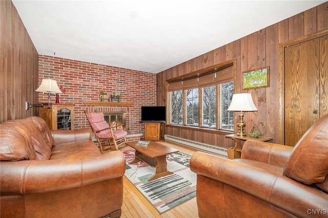 living area featuring a baseboard heating unit, a brick fireplace, and wooden walls